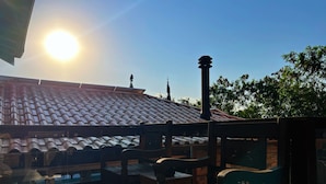 A wooden deck with a tiled roof, a chimney, and a view of the sky.
