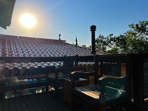 A wooden deck with a tiled roof, a chimney, and a view of the sky.