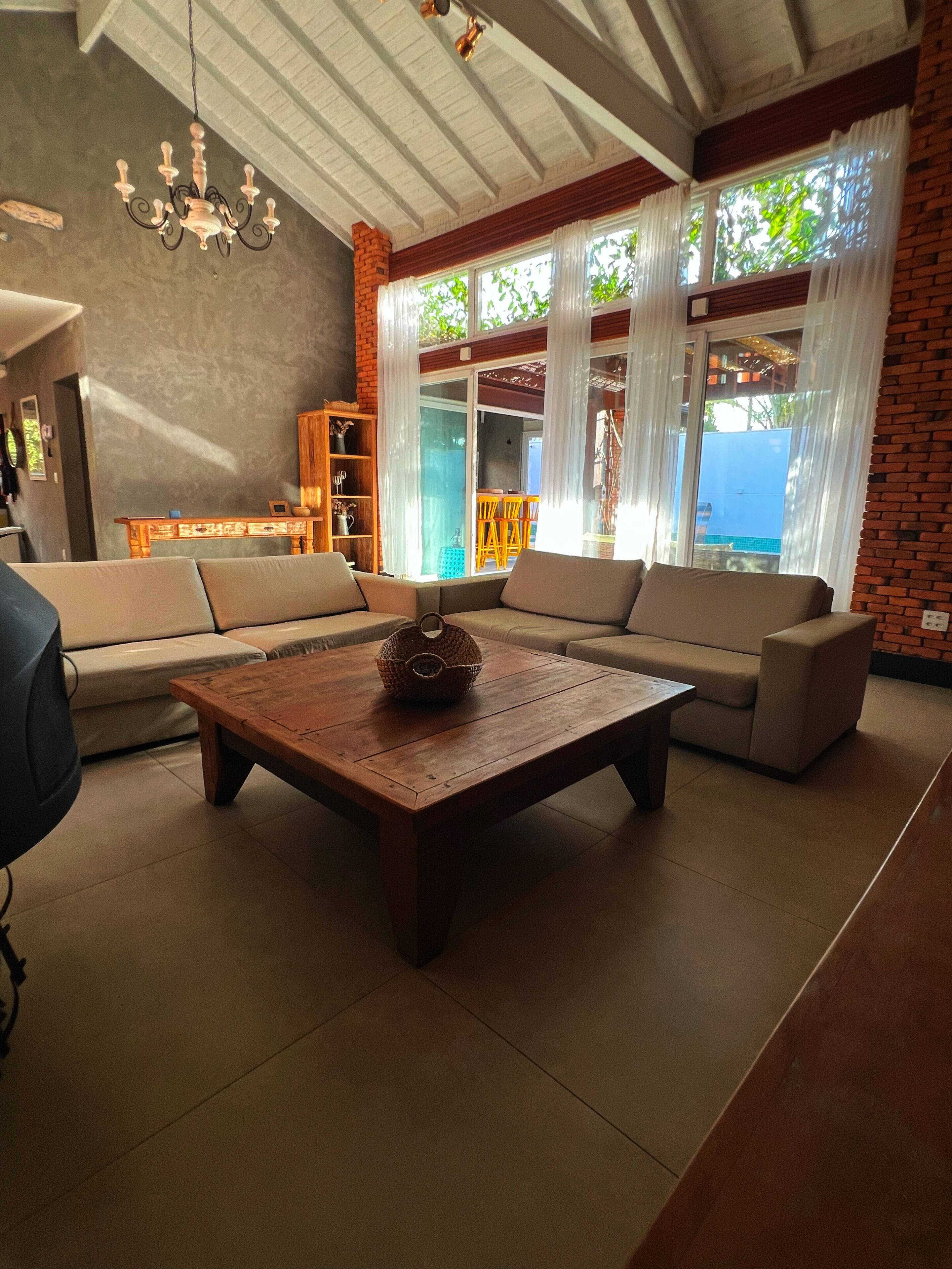A living room with a sofa set, a wooden coffee table, and a chandelier.