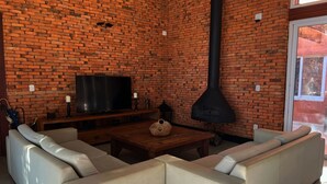 A living room with a brick wall, a television, a fireplace, and a sectional sofa.