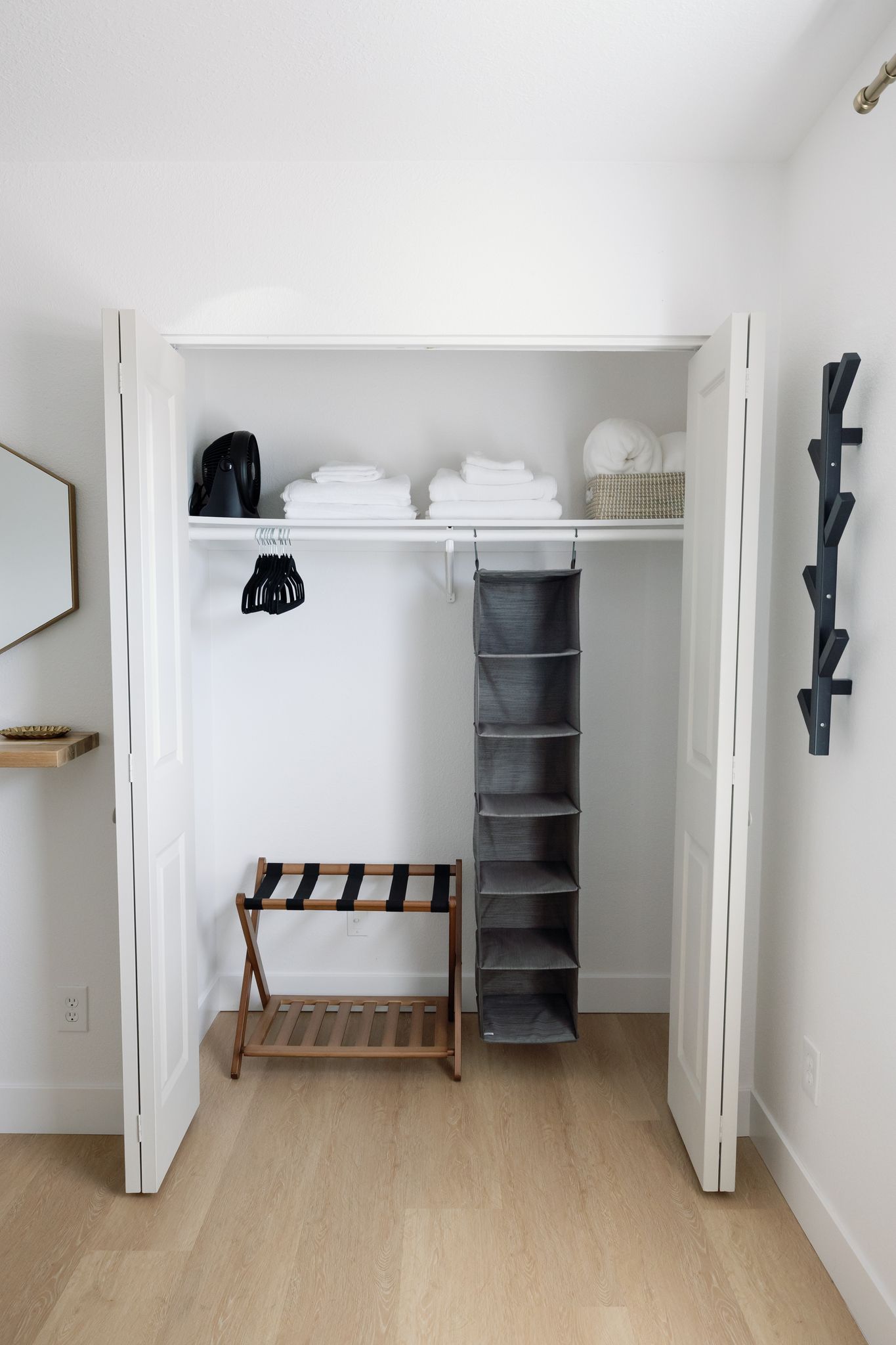 Un vestidor con estantes, un banco y espacio para colgar ropa.