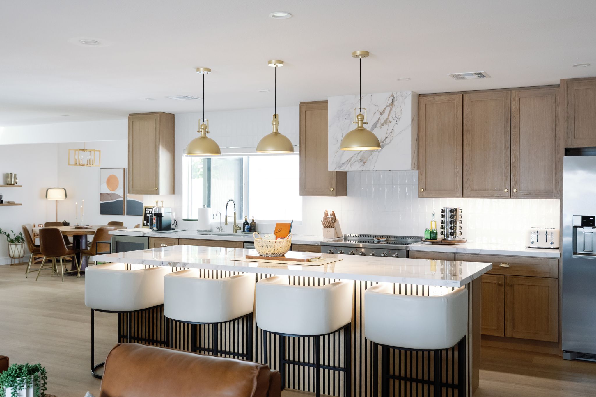 A modern kitchen with a central island, pendant lights, and wooden cabinets.