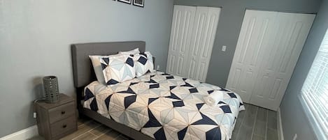 A bedroom with a bed, a ceiling fan, a nightstand, and a wardrobe.