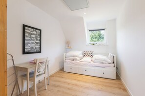Une chambre à coucher avec un lit, un bureau, une chaise, une fenêtre et une photo encadrée accrochée au mur.