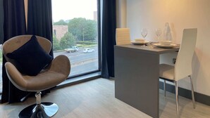 Ein modernes Zimmer mit Blick auf die Straße, einem Essbereich mit Tisch, Stühlen und einer Pendelleuchte.