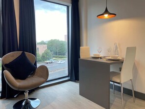 A modern room with a view of the street, a dining area with a table, chairs, and a hanging light fixture. - 33 Parkside - Coventry (Coventry)