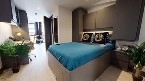 A modern bedroom with a large bed, bedside tables, a desk, and a chair.