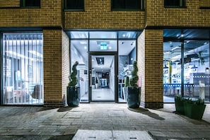 A hotel entrance with a glass door, potted plants, and a visible interior corridor. - 33 Parkside - Coventry (Coventry)