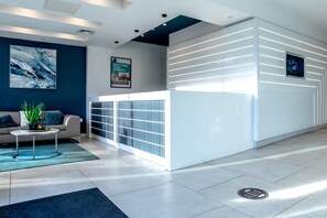 A modern reception area with a white reception desk, a sofa, and a coffee table. - 33 Parkside - Coventry (Coventry)