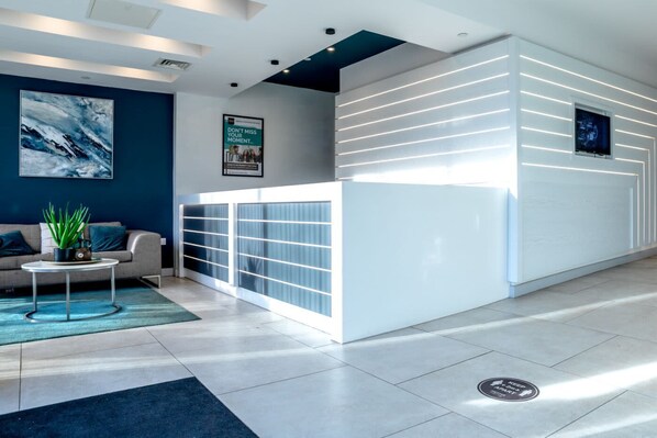 A modern reception area with a white reception desk, a sofa, and a coffee table.