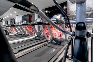 A treadmill with a digital display and a mirrored wall in the background.