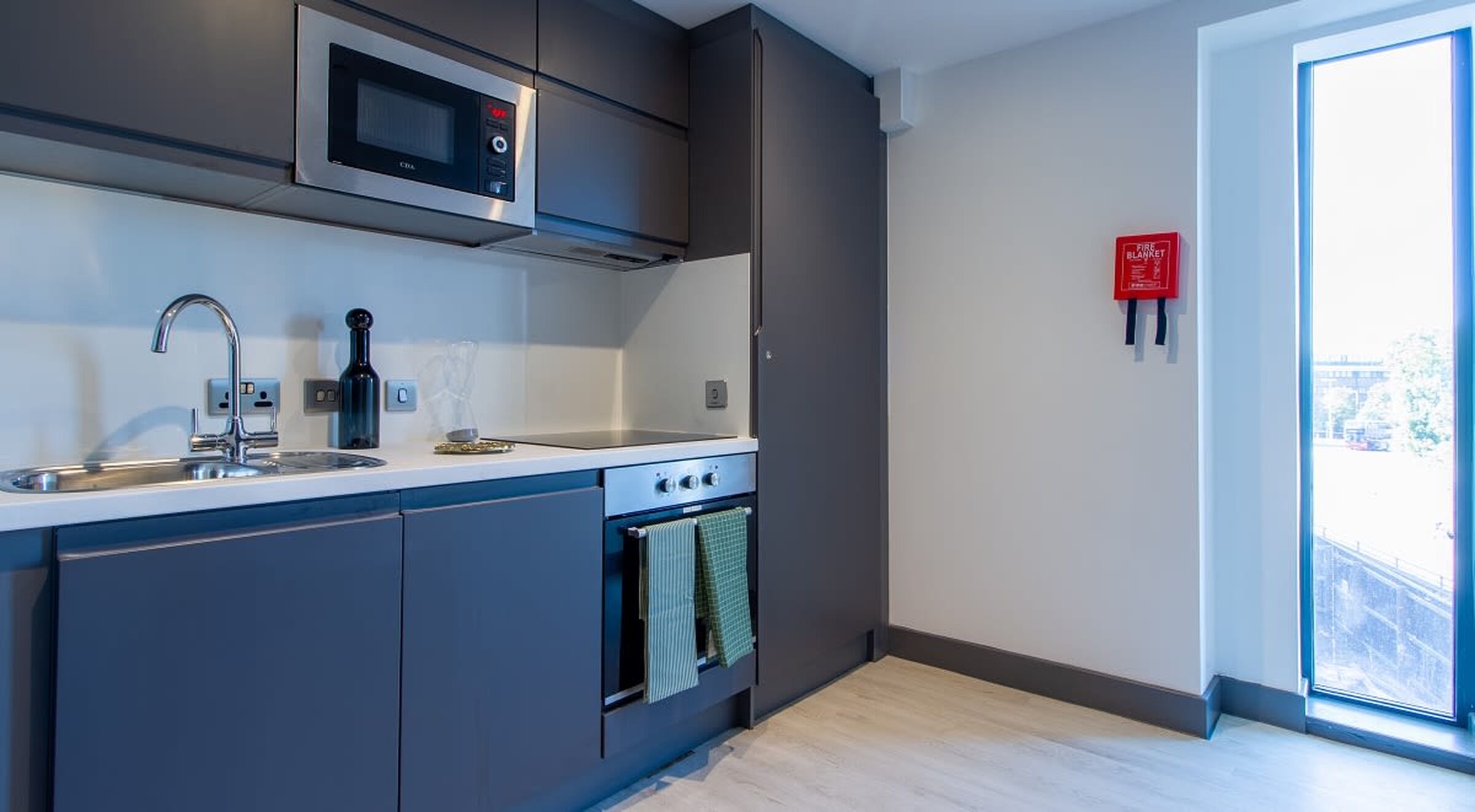 Een moderne keuken met een ingebouwde magnetron, een roestvrijstalen spoelbak en een fornuis.