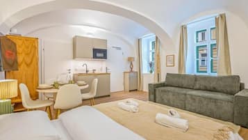 Una habitación de hotel con cama, sofá, mesa de comedor y kitchenette.