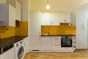 A compact kitchen with white cabinets, a washing machine, and a built-in oven. - cityswap- Wien Naschmarkt 2 (Wien)