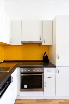 A kitchen with white cabinets, a black countertop, and a stainless steel oven. - cityswap- Wien Naschmarkt 2 (Wien)
