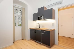 A compact kitchen with a microwave, sink, and dark cabinets. - cityswap- Wien Naschmarkt 2 (Wien)
