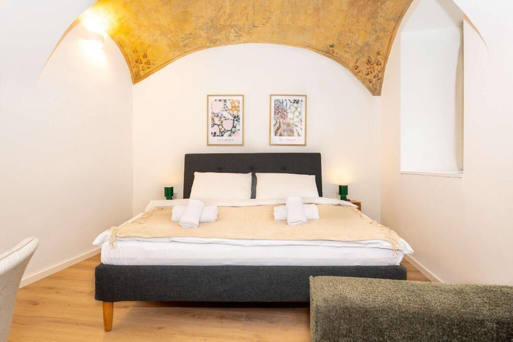 Ein Schlafzimmer mit einem Bett, zwei Wandbildern und einem Fenster.
