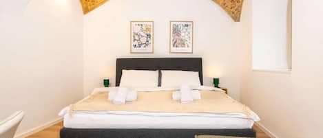 A bedroom with a bed, two wall-mounted artworks, and a window.