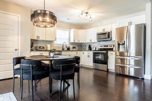 A modern kitchen with a central island, stainless steel appliances, and a chandelier. - The Grove Getaway - Modern Poolside Retreat (China Grove)
