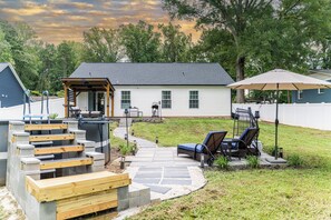 A backyard with a patio, outdoor furniture, a pergola, and a white house. - The Grove Getaway - Modern Poolside Retreat (China Grove)