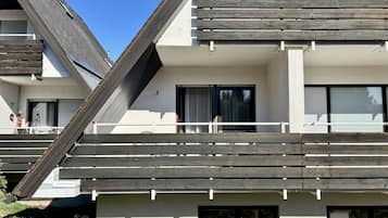 En moderne bygning med skråt tag, store vinduer og en balkon med trægelænder.