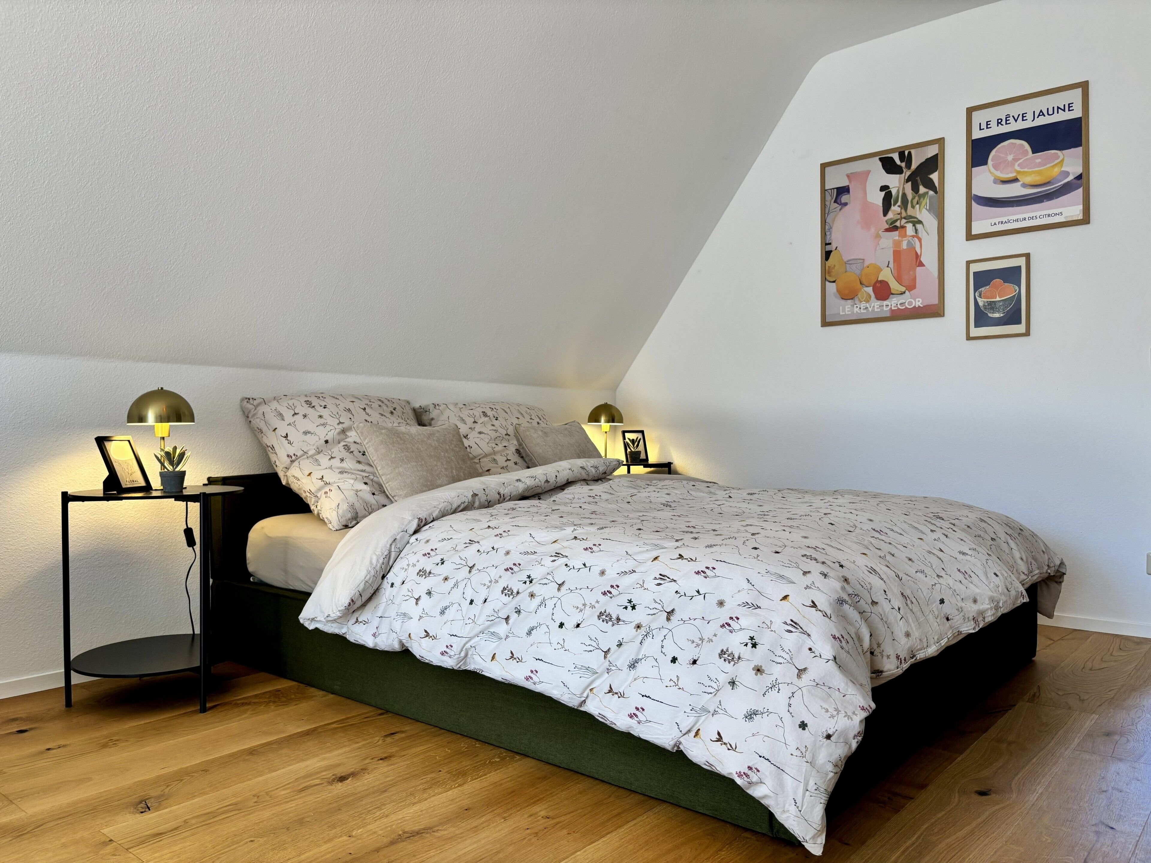 A bedroom with a bed, two bedside tables, a lamp, and wall art.