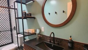 A bathroom with a round mirror, a sink, and a toilet.