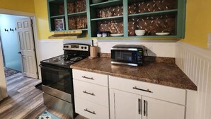 A kitchen with a stove, microwave, and shelves above the counter.