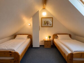 A bedroom with two wooden beds, a nightstand with a lamp, a small plant, and a wall-mounted picture. - A cozy vacation home right on Lake Wangermeer, sleeping up to 4 people, with two bedrooms, two bathrooms, and plenty of space to relax in the idyllic town of Gottels near Hohenkirchen. (Wangerland)