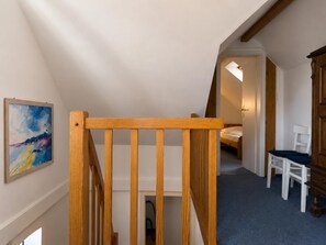 A staircase with wooden handrails leading to a bedroom with a bed and a chair. - A cozy vacation home right on Lake Wangermeer, sleeping up to 4 people, with two bedrooms, two bathrooms, and plenty of space to relax in the idyllic town of Gottels near Hohenkirchen. (Wangerland)