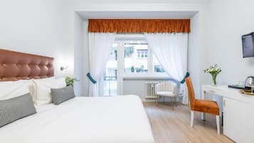 Ein Schlafzimmer mit einem Bett, einem Schreibtisch, einem Stuhl und einem Fenster mit Vorhängen.