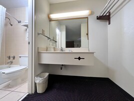 Un baño con inodoro, lavamanos, espejo y zona de ducha.