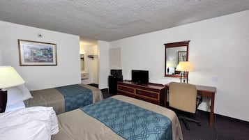 A hotel room with two beds, a desk, a television, and a mirror.