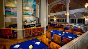 A spacious dining area with multiple tables and chairs, a bar area, and a large mural on the wall. - Orlando | Upscale Disney Stay | Pool + Spa (Lake Buena Vista)
