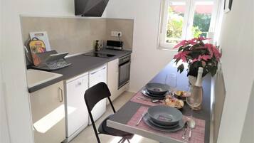 A compact kitchen with a dining area, equipped with a microwave, toaster, and a small oven.