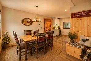 A cozy dining area with a wooden table and chairs, a chandelier, and a sign reading 'LAKE LIFE'. - CHILLBILLY BOLTON-Cozy & Convenient 3BR/2BA ADK home W/HOT TUB in Bolton Landing (Bolton Landing)