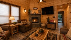 Ein gemütliches Blockhaus-Interieur mit Kamin, Ledermöbeln und einem Flachbildfernseher.