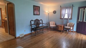 A living room with a wooden bench, two chairs, a small table, a floor lamp, and a door. - Quiet Ranch Retreat, Close to Everything with Outdoor Bar & Field Views (Boardman)