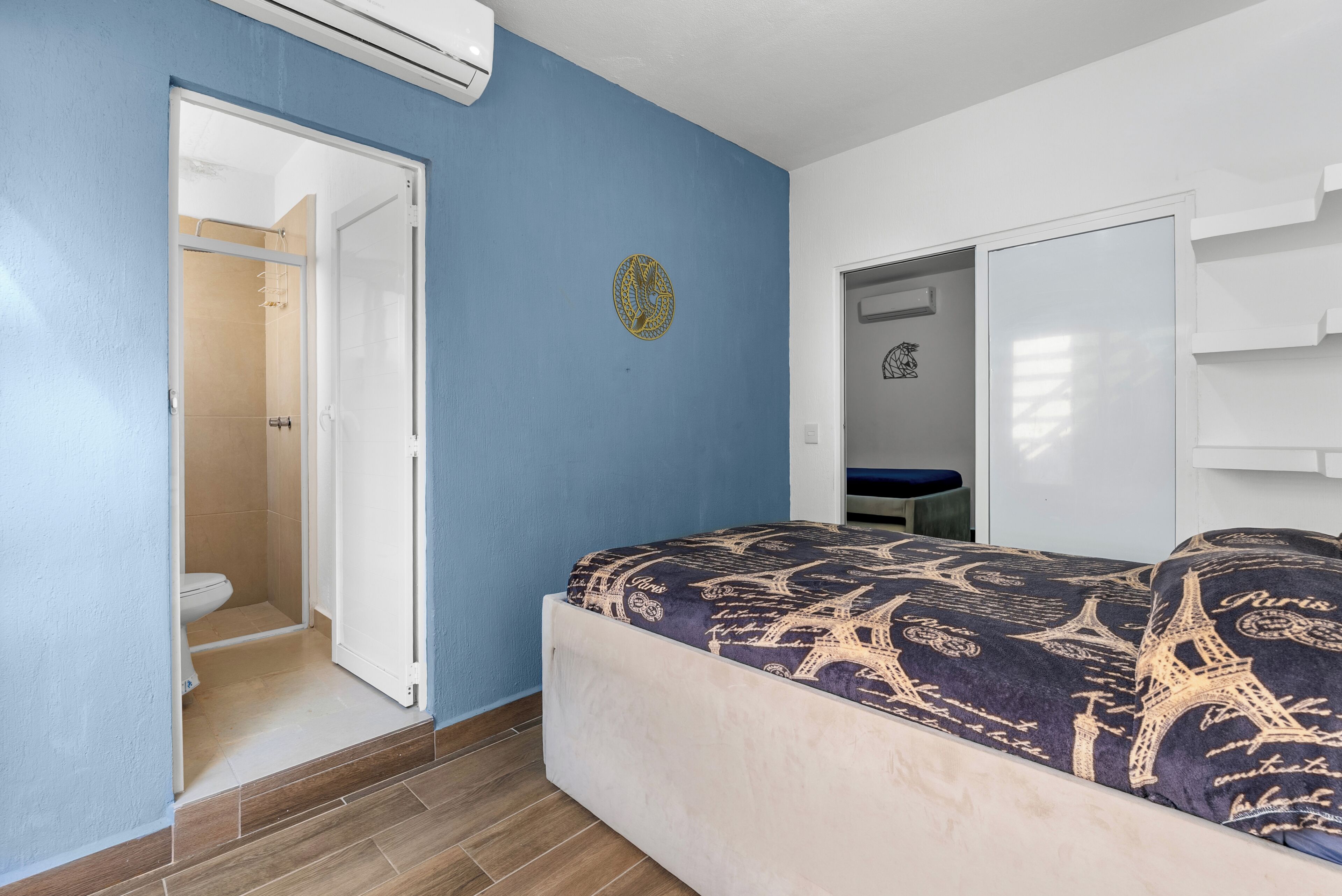 Een slaapkamer met een bed, een kledingkast en een badkamer met douche.