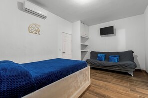 Une chambre équipée d’un lit, d’un canapé, d’un téléviseur à écran plat et d’un appareil de climatisation.