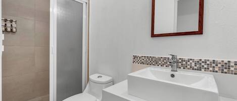Une salle de bain avec des toilettes, une douche et un lavabo.