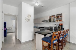 A modern kitchen with a central island, wooden chairs, and a dining area. - Casa Ivarica Spacious Home for 16 in Residential (Mezcales)