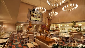 Un'ampia sala da pranzo con soffitti alti, lampadari decorativi e una statua centrale a forma di cavallo.