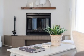 Ein Wohnzimmer mit einem weißen Tisch, einem Buch mit dem Titel 'Connect with Nature' und einer Topfpflanze.