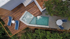 A rooftop pool area with a wooden deck, lounge chairs, and a small table.