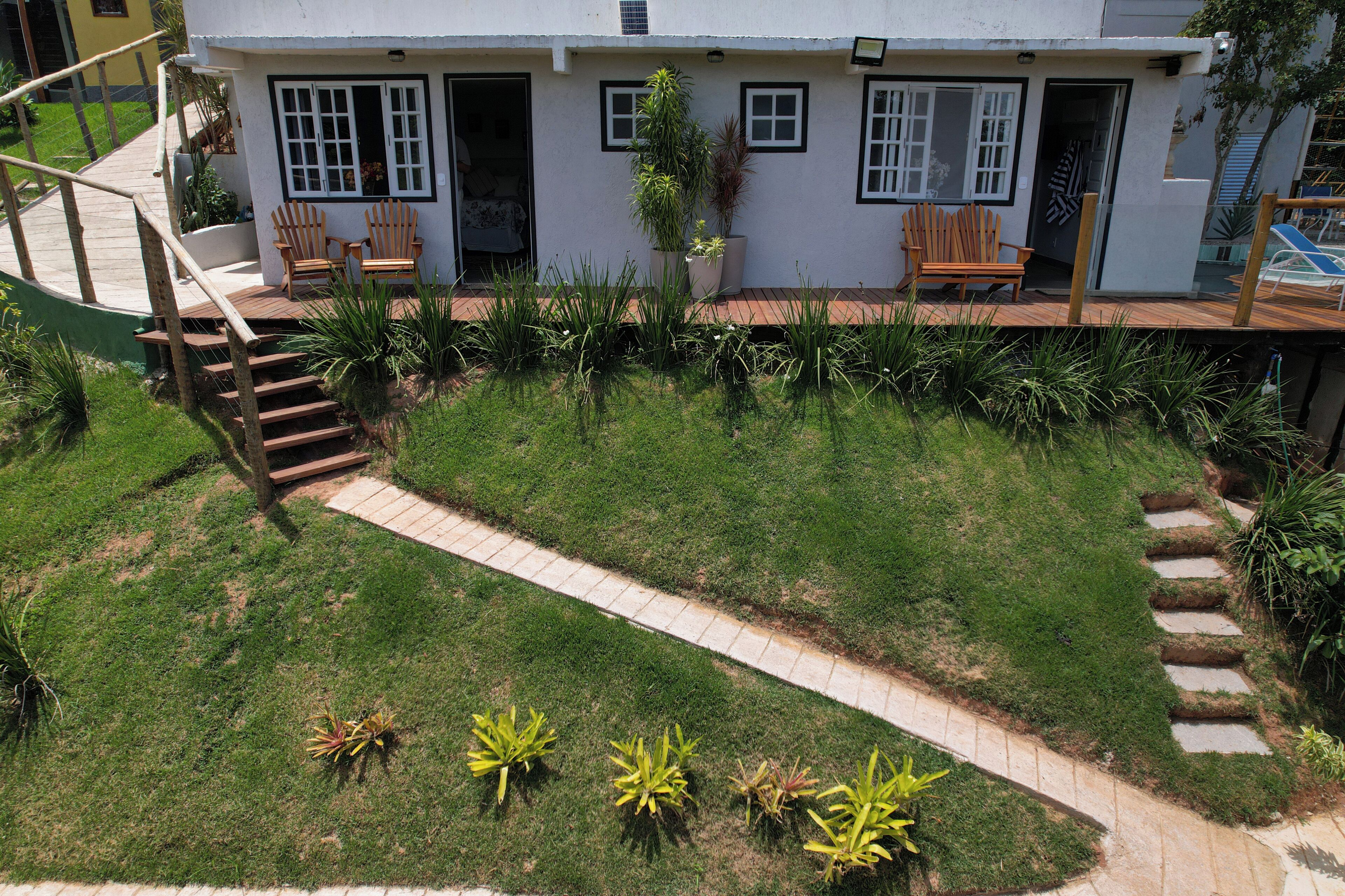 A two-story house with a front porch, a staircase leading to the upper level, and a well-maintained lawn with small plants.