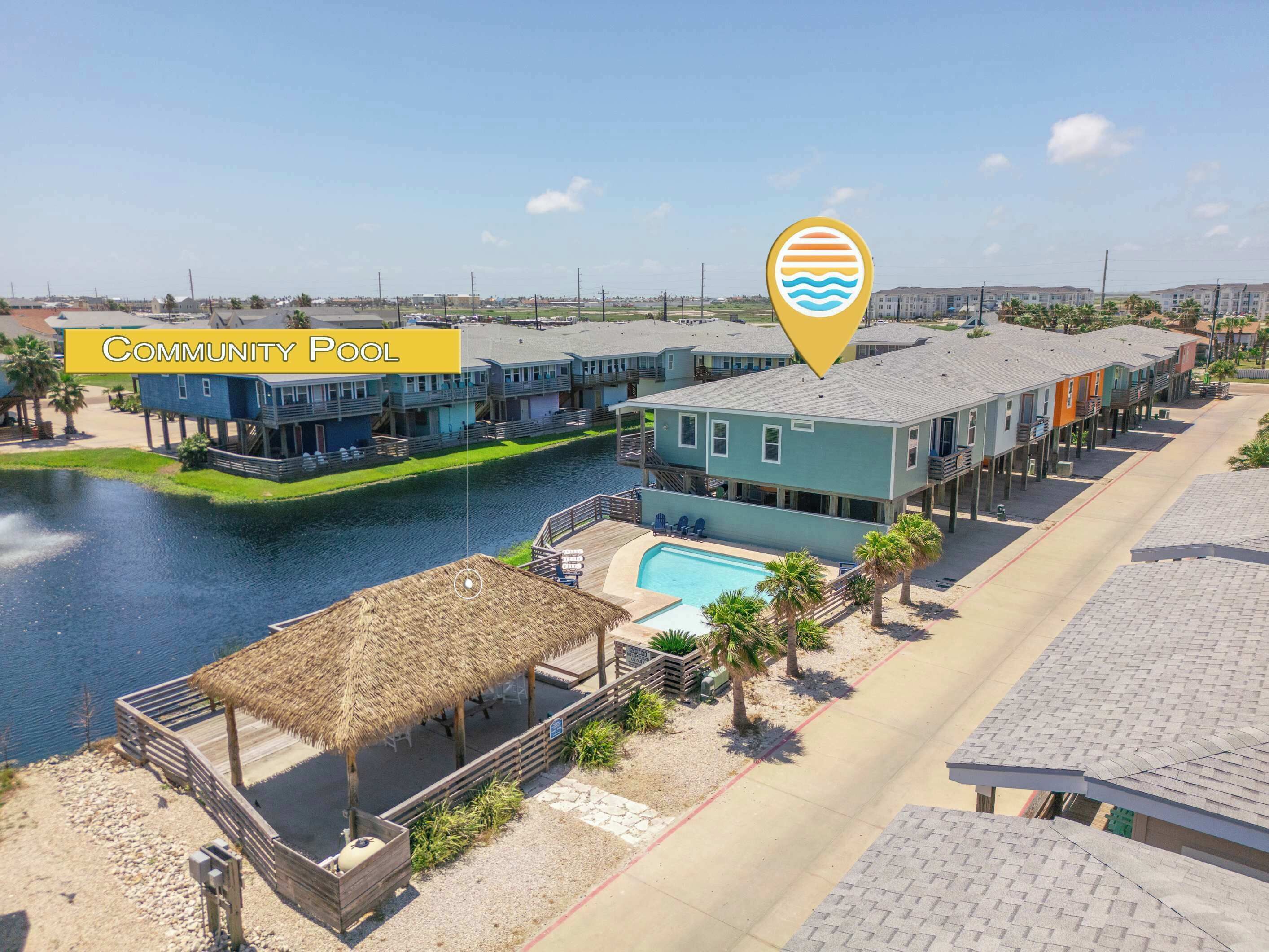 A community pool area with a water body, wooden deck, and buildings with balconies.