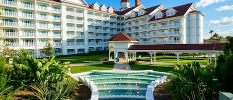 A large hotel with multiple balconies, a central courtyard, and a swimming pool.