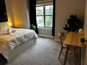 A bedroom with a bed, a bedside table, a window, and a small table with a chair. - Moose - Private Bedroom near Downtown and 17th Av (Calgary)