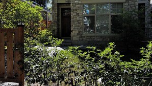 A stone house with a wooden gate, a stone pathway, and a small pond. - Grizzly - Private Luxury Unit near DT and 17th Av (Calgary)